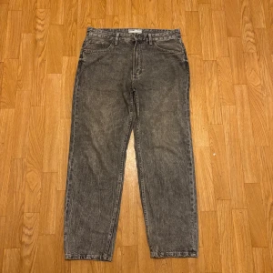 Grå '90s wide jeans från Bershka - Säljer ett par gråa jeans från Bershka i modellen '90s wide'. De har en snygg tvättad look, raka ben och bred passform. Klassisk femficksdesign och hög midja. Perfekta för dig som gillar retrovibbar och avslappnad stil.