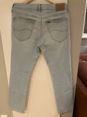 Ljusblå Lee jeans med raka ben - Säljer ett par ljusblå jeans från Lee med klassisk femficksdesign och raka ben. Jeansen har Lee-lapp bak i midjan och snygga sömdetaljer på bakfickorna. Perfekta för en avslappnad och trendig look. Hör av er vid minsta fundering 😌😌