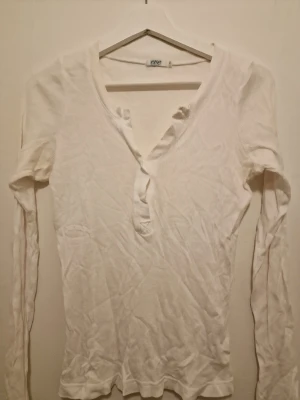 Vit ribbad långärmad topp  - Vit ribbad långärmad topp från Eve Nette med v-ringning och en slim passform.