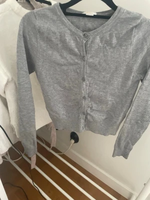 Grå kofta med knappar Gina Tricot (liten i storleken) - Snygg grå kofta från Gina Tricot med rund halsringning och knäppning framtill. Modellen är kortare och har långa ärmar. Perfekt att slänga över en topp för en enkel och stilren look💕🍪