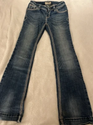 Blå bootcut jeans med kontrastsömmar - Snygga blå mid/low waist bootcut jeans med markerade kontrastsömmar och klassiska fem fickor. Jeansen har en lätt tvättad look och är tillverkade i jeansmaterial. Perfekta för dig som gillar en avslappnad men trendig stil. Dem är bara använda några fåtal gånger och har därför inga synliga defekter 💞💞
