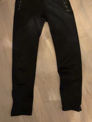 Svarta byxor från BOSS med smal passform - Snygga svarta byxor från BOSS med smal passform och diskreta detaljer vid fickorna. Byxorna har en klassisk look och är perfekta för dig som gillar stilrena plagg. Materialet känns mjukt och stretchigt för extra komfort.