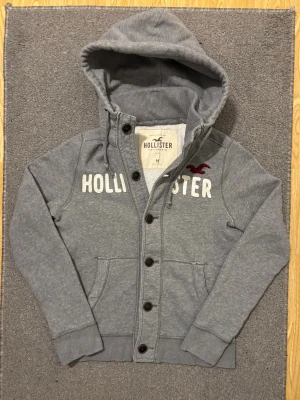 Vintage Hollister Cardigan Med Knappar  - Säljer denna mycket snygga och sällsynta Hollister cardigan | Storlek M | Mycket bra skick utan defekter | Längd ≈ 63cm, Bredd armhåla - armhåla 53cm | Modell 175, 68kg | Hör av vid funderingar!!