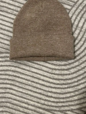 Beige ribbad mössa - En stilren beige mössa i ribbstickat material. Klassisk modell med uppvikt kant som passar perfekt till höst och vinter. Enkel att matcha med olika outfits och håller dig varm under kalla dagar.