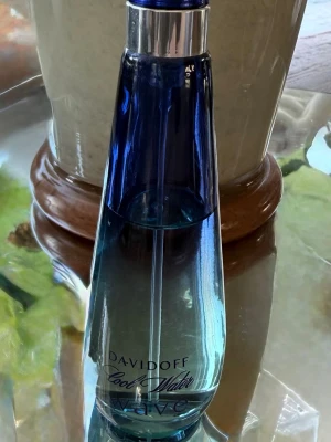 Davidoff Cool Water Wave parfym - Fräsch parfym från Davidoff i serien Cool Water Wave. Flaskan är tillverkad i glas och har en snygg blå ton som går från mörkblått upptill till ljusare blått nedtill. Flaskan har en elegant, avsmalnande form och ett silverfärgat lock. Perfekt för dig som gillar marina och fräscha dofter. Ca 75% kvar.