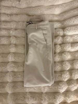 Vita kostymbyxor från Bik Bok - Snygga vita kostymbyxor från Bik Bok med klassisk rak passform och diskreta fickor. Byxorna har hällor för bälte och är tillverkade i ett mjukt material som känns bekvämt hela dagen. Perfekta för en clean och stilren look.