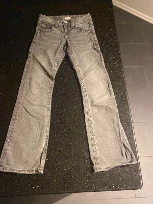 Grå bootcut jeans från Gina Tricot - Snygga grå jeans med bootcut-modell och klassisk femficksdesign. Jeansen har normal passform och är tillverkade i denim med en lätt tvättad look. Perfekta för dig som gillar en avslappnad men trendig stil.