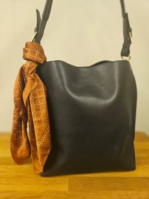 H&M svart handväska med gulddetaljer- rymlig och nyskick  - Stilren svart handväska med guldfärgade spännen. Passar bra för både jobb och fritid. I jättefint skick. 