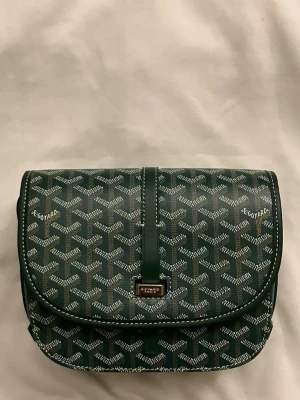 Grön axelväska  - Jag säljer en grön axelväska i läder. Den har bra kvalitet och en elegant stil. Den är 22cm bred och 17cm hög. Väskan är perfekt för liten extra till ens outfit.