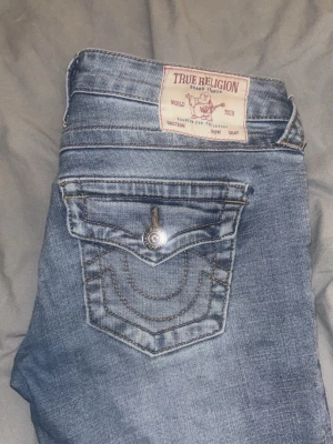 True Religion ljusblå jeans - Ljusblå jeans från true religion i deras vintage kollektion. Köpta för 1599 på jeansbolaget. Uppsydda i butik så jag som är 1,59 kan ha dem. I fint skick men använda. Bootcut och jätte lågmidjade.