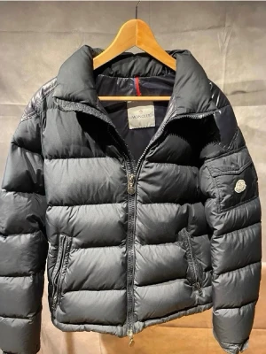 Moncler chevalier jacka - Säljer min moncler chevalier jacka då den var för liten, jackan är i 9/10 skick de som märks är att bilden inne i jacka släppt lite.       Jackan är självklart äkta och är köpt från vongreven closet.  (Strl är 3 vilket motsvarar M. )Hör gärna av dig om du undrar över något! Om priset inte passar så skicka gärna ett nytt så ska vi kunna komma överens! MVH Nils