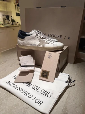 Golden goose superstar GGDB skor  - Tjena!! Säljer mina helt nya och svin feta golden goose superstar i vit och marinblå färg!! Skorna är slut överallt inpricip och finns inte billigare för ett par nya🙌 original pris: 5500kr, mitt pris: 2199kr