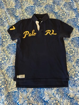 Vintage Ralph Lauren piké - Snygg marinblå piké från Polo Ralph Lauren i storlek S (passar även XS). När jag köpte den begagnat kom den med två fläckar, dock är de knappt synliga när man har på sig den. Det som är strax under ärmarna kallas ”lufthål”