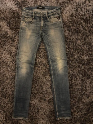 Replay ljusblå jeans. 28-32 - Snygga ljusblå jeans från Replay med klassisk femficksdesign och slitna detaljer. Jeansen har läderpatch med Replay-logga bak i midjan och är tillverkade i mjukt denimtyg. Perfekta för en trendig och avslappnad look.