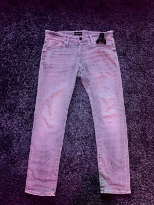 Gråa slim jeans från Jacknjones - Snygga gråa jeans från Jacknjones med klassisk femficksdesign och smal passform. Jeansen har en modern look med raka ben och subtila slitningar. Perfekta för dig som gillar en stilren och avslappnad vibe.