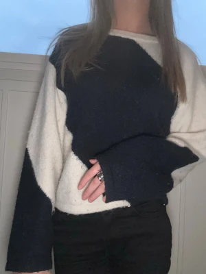 Oversized stickad tröja i svartvitt - Säljer en oversized stickad tröja med coolt svartvitt mönster. Tröjan har breda ärmar och en avslappnad passform, perfekt för en trendig och bekväm look. Materialet är mjukt och fluffigt, vilket gör den extra skön att bära.