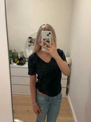 Mörkblå ribbad topp med v-ringning - Snygg mörkblå topp med v-ringning och korta ärmar. Toppen har ett ribbat mönster som ger en extra touch och är lätt att matcha till olika outfits. Perfekt för dig som gillar en enkel men stilren look.