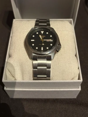 Seiko 5 automatic - Säljer min seiko 5 automatic! Helt ny. Köptes förra veckan och har fortfarande plasten på glasbaksidan kvar! Box, kvitto och extra länkar följer med! Den är i jättebra skick och har inga tecken alls på användning! Nypris 3898kr BVSA!