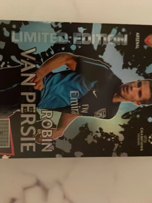 Limited Edition Robin van Persie kort - Samlarkort med Robin van Persie i Arsenal-tröja, Limited Edition-version. Kortet har svart och blå bakgrund med silvertext och klubbmärke. Perfekt för dig som gillar fotboll och vill utöka din samling med något unikt.