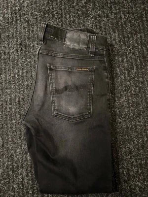 Nudie jeans tight terry - Säljer ett par svarta skinny jeans från Nudie Jeans i storlek W31 L30. Jeansen har klassisk femficksdesign, svarta sömmar och diskret tvättad look. Materialet är mjukt och stretchigt jeans, perfekt för dig som gillar en tight passform.