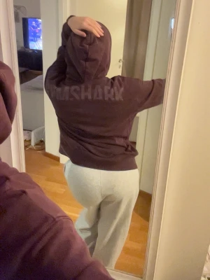 Mörklila hoodie från Gymshark - Säljer en mörklila hoodie från Gymshark med stor huva och tryckt logga på ryggen. Hoodien har en avslappnad passform och är tillverkad i mjukt material, perfekt för chill eller träning. Snygg och enkel att matcha med andra plagg.
