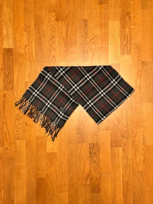 Grå Burberry halsduk - Säljer en grå halsduk från Burberry. Halsduken är i gott skick och är gjord i 100% lamull. Var inte rädd för några frågor. Pris diskuteras inte!
