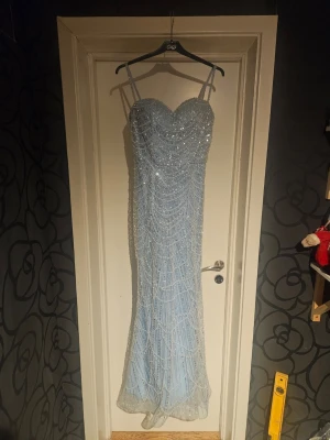 Ljusblå balklänning stl s - Så vacker balklänning i ljusblått med pärlor som glittrar vackert, fint skick men finns en antydan till svaga fläckar inuti av brun utan sol, dessa är dock väldigt diskreta! Det har sytts i en bh för snyggare form men denna går att sprätta bort om man vill! Säljes I befintligt skick, undrar man något eller vill se fler bilder är det bara att fråga!