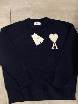 Mörkblå stickad tröja från Ami Paris - AMI Paris tröja – helt ny. Oanvänd och i nyskick. Klassisk design med den ikoniska AMI-loggan. Strl S men passar mer som M Skickas supersnabbt 📦 Skriv vid frågor!
