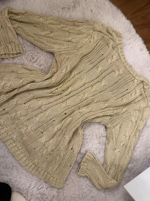 Beige stickad tröja med flätmönster - Säljer en beige stickad tröja med snyggt flätmönster och ribbade muddar. Tröjan har en avslappnad passform och långa ärmar, perfekt för lager på lager. Materialet känns mjukt och skönt mot huden.