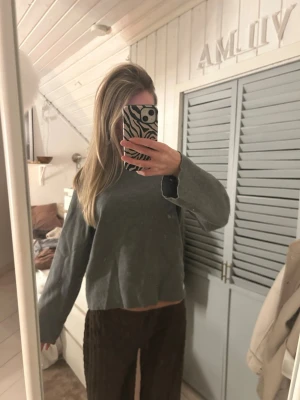 Grå basic stickad tröja - En enkel grå stickad tröja med rund halsringning och långa ärmar. Tröjan har en rak passform och ribbade muddar vid halsen. Perfekt för lager-på-lager och passar till det mesta i garderoben.