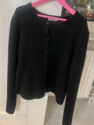 Svart fluffig kofta f - Mysig svart kofta från Gina tricot med fluffig yta och rund halsringning. Koftan har knäppning framtill med svarta knappar och långa ärmar. Perfekt för lager-på-lager och en stilren look.