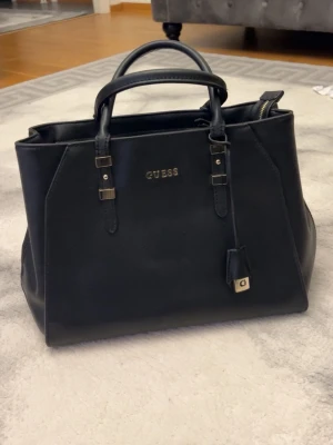 Svart handväska från Guess - Köptes för 2199 riktigt bra skicka använd endast 2-3 gånger riktigt snygg väska som passar med nästa allt 
