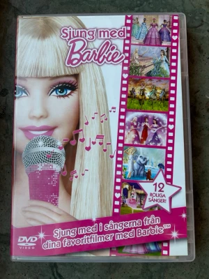 Sjung med Barbie dvd - DVD med sånger från dina favoritfilmer med Barbie. Innehåller 12 roliga sånger och bonus-musikvideos med lyrics så man kan sjunga till.  Ingår en poster!  Finns på språk: Svenska, Engelska, Finska  OBS!! skivorna är begagnade så det kan förekomma repor/hairlines på skivorna, men då jag kollar igenom alla filmer jag säljer garanterar jag att alla funkar felfritt om inget annat står! :)