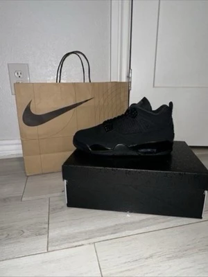 Nike Air Jordan 4 Retro Svart - Nike Air Jordan 4 Retro i helsvart färg, med meshpaneler och detaljer i syntet och skinn. Klassisk siluett med snörning och platt sula, samt synlig Air-enhet i hälen. Perfekt för dig som gillar stilrena sneakers med ikonisk design.