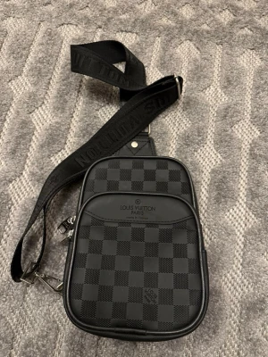 Lv väska - Snygg axelväska från Louis Vuitton i svart med klassiskt rutigt mönster och justerbar axelrem. 