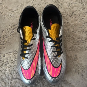 Nike Hypervenom Liquid Diamond (Silver, Rosa och guld) fotbollsskor - Sällsynta och stilrena fotbollsskor i exklusiv Liquid Diamond-design. Skorna kombinerar lättvikt, bra touch på bollen och grym passform. Färgen silver/rosa gör dem riktigt iögonfallande på planen. Perfekta för dig som vill sticka ut och prestera på topp. Pris kan diskuteras 