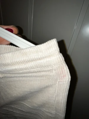 Beiga manchesterbyxor från Wera - Snygga beiga manchesterbyxor från Wera med breda ben och klassisk femficksdesign. Byxorna har hög midja, dragkedja och knapp framtill samt bälteshällor. Mjukt manchestertyg som ger en chill och retro vibe.