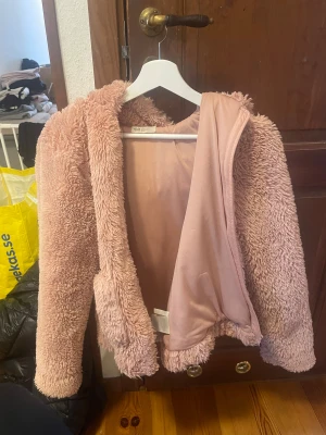 Rosa teddyjacka - Fluffig teddyjacka från H&M i en ljusrosa ton. Jackan har långärmade ärmar och är tillverkad i mjukt syntetmaterial med slät insida. Perfekt för dig som gillar mysiga och trendiga plagg med oversized känsla.