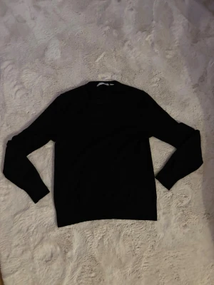 Svart tiger of sweden tröja med rund hals. Nypris 1350kr. - En stilren svart stickad tröja med rund hals och långa ärmar. Perfekt för dig som gillar enkel och klassisk design. Tröjan har en normal passform och är mjuk mot huden, vilket gör den skön att bära under kyligare dagar.