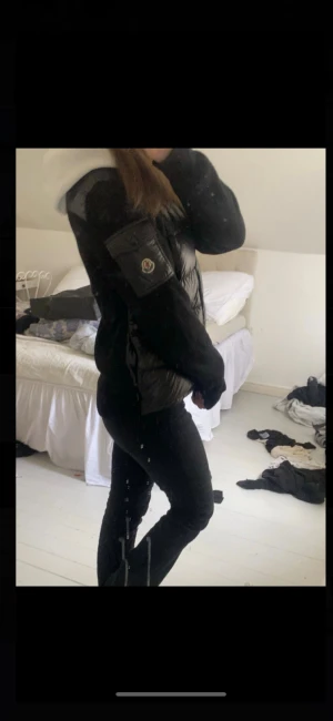 Svart pufferjacka/cardigan från Moncler - Svart pufferjacka från Moncler med glansig, quiltad front och stickade ärmar. Jackan har hög krage, dragkedja framtill och en ficka med Moncler-logga på ärmen. Perfekt för dig som gillar stilren och sportig look. Äkta, har påsen till den.