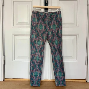 Mönstrade byxor från COS - COS-byxor med unikt mönster och välskräddad design. Modellen är rak med normal tajt passform och normal/hög midja. Materialet är följsamt med lite stretch. Funkar alla årstider, både vardag och fest. Byxan slutar vid ankeln på modellen som är 165cm /strl S. Perfekt byxa för att sticka ut med färg och mönster i kombination med basplagg. 