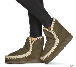 Mou skor - Säljer ett par olivgröna boots i mocka med beige, stickad kant runt öppningen och längs sulan. Skorna har platt sula och rund tå, perfekta för kalla dagar. De är fodrade och har en mysig, avslappnad look som passar till jeans eller leggings. Helt nya! Nypris är 2800!