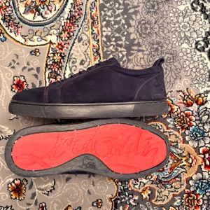 Mörkblå sneakers från Louboutin - Snygga mörkblå sneakers från Christian Louboutin med klassisk röd sula och signatur på hälen. Skorna har rund tå, platt sula och snörning framtill. Perfekt för dig som gillar exklusiv streetstyle. Pris kan diskuteras vid snabb affär.