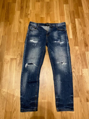 Blå distressed jeans Supply & Demand - Snygga blå jeans från Supply & Demand med slitna detaljer. W 32 funkar även w 31 L 33/34. Pris 399kr