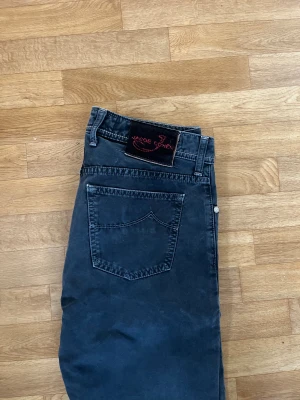 Jacob Cohën Type 688 svarta jeans - Snygga svarta jeans från Jacob Cohën, modell Type 688. Byxorna har raka ben, klassisk femficksdesign och silverfärgade knappar. Tillverkade i mjuk bomull med detaljer i vinrött på insidan. Perfekta för dig som gillar stilrena och exklusiva jeans.