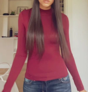 Vinröd polotopp med lång ärm - Säljer en vinröd polotopp med lång ärm och tight passform. Toppen har en enkel design utan mönster och är tillverkad i ett mjukt, stretchigt material som sitter snyggt mot kroppen. Perfekt att styla med jeans eller kjol för en clean look.