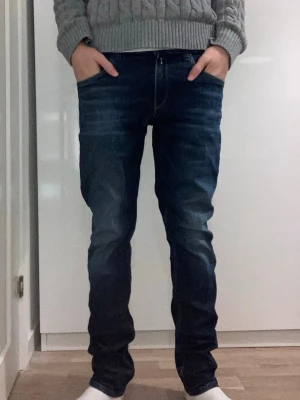 Replay jeans W31/L32 - Säljer ett par Replay Wallys jeans i mörkblå tvätt med snygga slitningar och klassisk femficksdesign. Jeansen har slim fit passform. W31, L32