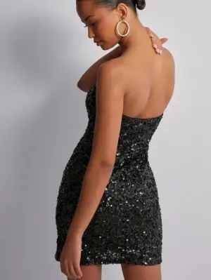 Säljer en svart, axelbandslös kortklänning med glittriga paljetter över hela klänningen. Använd 2 gånger och har inga defekter. Perfekt till nyår!