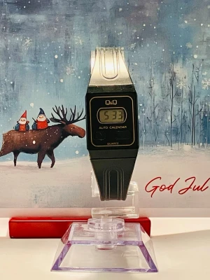 Cool retro Q&Q klocka  - Till salu en retro Q&Q armbandsur med quartz urverk. Klockan har en digital display med auto kalender. Boetten och  armbandet är tillverkade av plast. Baksidan är tillverkad av rostfritt stål. Passar perfekt i samband med träning, yoga mm. Säljes i befintligt fungerande skick enligt bilderna, rustad med nytt batteri!   