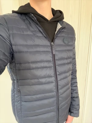 Mörkblå dunjacka från Armani Exchange - Snygg mörkblå pufferjacka från Armani Exchange med diskret logopatch på bröstet. Jackan har horisontella quiltade sömmar, dragkedja framtill och två sidofickor med dragkedja. Perfekt för kyliga dagar och har en stilren look som funkar till många outfits. Pris kan diskuteras, hört av dig vid minsta fråga!